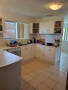 a kitchen with white cabinets and a tile floor at Sandi's Guest House For two in Gladstone