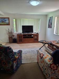 a living room with two couches and a flat screen tv at Sandi's Guest House For two in Gladstone +1 photo