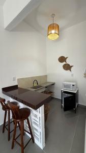 a kitchen with a counter and a sink and two stools at O Caminho das Dunas in Jericoacoara