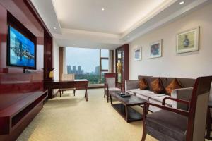 a living room with a couch and a table and a television at Wuhan Gaotie Kairui International Hotel in Wuhan