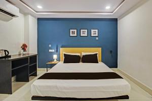 a bedroom with a large bed with a blue wall at Super Hotel O Qualia Miyapur in Hyderabad +24 photos