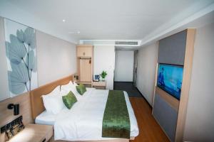 a bedroom with a large white bed and a flat screen tv at GreenTree Inn Tangshan Nanhu International Exhibition Center in Tangshan