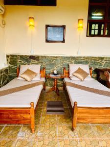 two beds sitting in a room with a table at The Forest Inn Kandy in Kandy