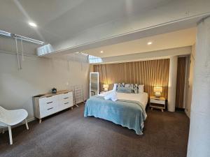 a bedroom with a bed and a dresser and two lamps at Beautiful Apartment Surrounded by Native Bush in Picton
