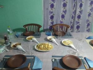 a table with a plate of food and spoons on it at Dinu Homes Stay in Haputale