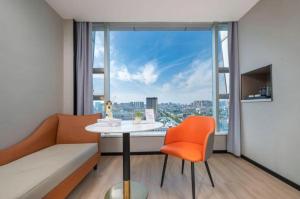 Cette chambre comprend une table, une chaise et une grande fenêtre. dans l'établissement Borrman Hotel Yongzhou Lingling Ancient Town Government, à Guzhuting