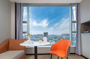 ein Raum mit einem Tisch und orangefarbenen Stühlen und einem großen Fenster in der Unterkunft Borrman Hotel Yongzhou Lingling Ancient Town Government in Yongzhou