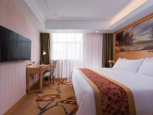 ein Hotelzimmer mit Bett, Schreibtisch und Fernseher in der Unterkunft Vienna Hotel Shenzhen Guanlan Shanshuitianyuan Xintian in Tiantangwei + 135 Fotos