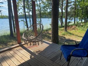 a hammock and a chair on a porch with a lake at Jazinks Sunset 4 in Apšenieki