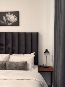 a bed with a black headboard and a table with a lamp at InWeFT Coastal Homes Apartment B in Swakopmund