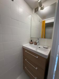 een badkamer met een wastafel en een spiegel bij La Plage Studio lumineux, balcon vue mer in Les Sables-dʼOlonne