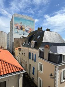 een uitzicht op daken van gebouwen met een muurschildering bij La Plage Studio lumineux, balcon vue mer in Les Sables-dʼOlonne +3 foto's