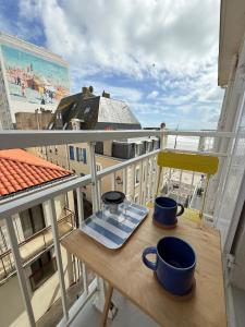 een tafel op een balkon met twee mokken erop bij La Plage Studio lumineux, balcon vue mer in Les Sables-dʼOlonne