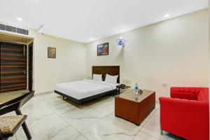 a bedroom with a bed and a red chair at Hotel O Kinsfolk Inn in Ghaziabad