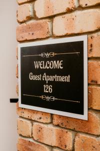 a sign on a brick wall that reads welcome guest apartment at Kennedy Drive Boutique Motel & Nursery- Close To City Centre & Airport - 24 Hour Self Check-In in Tweed Heads