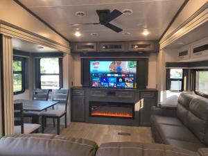 a living room with a tv and a fireplace in a rv at Luxury Glamping in the Mile High - Private pool, Hot Tub, and Outdoor Fire Pit!! in Westminster