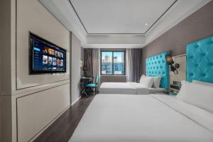 a hotel room with two beds and a flat screen tv at Xana Hotelle Chongqing Jiefangbei Center Branch in Chongqing