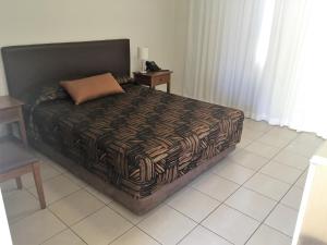 ein Schlafzimmer mit einem Bett und zwei Nachttischen in der Unterkunft Swag Motel in Middlemount