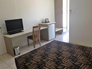 a room with a desk with a television and a chair at Swag Motel in Middlemount