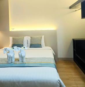 a bedroom with a large white bed with two baby towels at The Regizt Jomtien Pattaya in Jomtien Beach