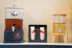 eine Arbeitsplatte mit einem Mixer und Pappbechern in der Unterkunft Jun Hotel Guangxi Wuzhou Changzhou District Fengye Garden in Wuzhou