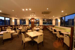 a restaurant with tables and chairs and windows at Sunwest Hotel Sasebo in Sasebo