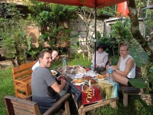 a group of people sitting around a table with food at Landak River Guest House Jungle Trekking Only Booking with Us in Bukit Lawang