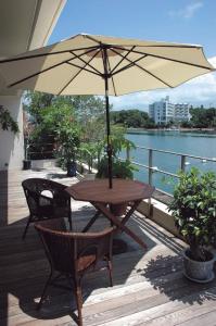 白浜町にあるホテル ルアンドン白浜の木製テーブル、椅子、パラソル付きのデッキ