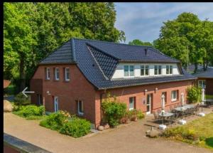 a large red brick house with a black roof at Ferienhaus BODDEN- vis-a-vis Hiddensee für bis zu 15 Gäste in 7 Appartements in Schaprode +8 photos