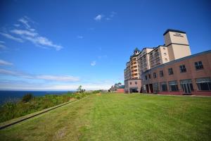 eine Wiese neben einem Gebäude und dem Meer in der Unterkunft Hotel Grand Mer Sankaiso - Vacation STAY 69634v in Kawajiri