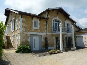 a large brick house with a balcony on top at Le Chalet des Vignes in Saint-Laurent-des-Vignes