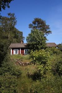 a red house on top of a hill with trees at Vuohensaari Camping Ahtela's cottage in Salo