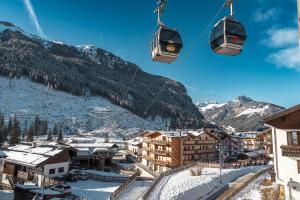 a ski lift over a town with snow covered mountains at Cesa Planber Apartments Mountain View SKI-IN SKI-OUT in Canazei