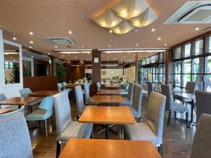 a restaurant with wooden tables and chairs and windows at Rembrandt Inn Kazusa in Kimitsu