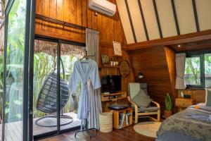 a bedroom with a bed and a tv and a window at Kabinji Bali in Tampaksiring