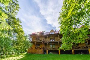 una grande casa in legno con alberi di fronte di Полярис Polyaris a Jaremče