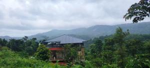 a house on a hill with mountains in the background at Nisarga Coorg Home Stay in Somvārpet +20 photos