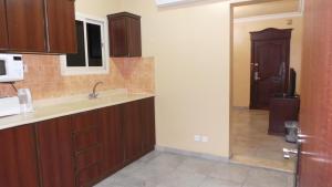 a kitchen with wooden cabinets and a door to a hallway at ضيافة بيت المسرة للشقق المخدومة in Al Khobar +32 photos