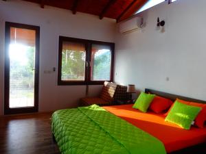 a bedroom with a large bed with green and orange sheets at Karali Apartments in Lagadin