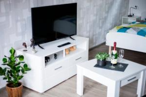 un centro de entretenimiento blanco con TV y mesa en Hoofer Apartments, en Schauenburg