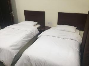 two beds sitting next to each other in a bedroom at Al Noor Saadah Furnished Apartments in Salalah
