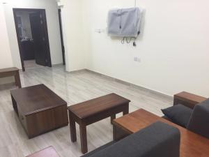 ein Wohnzimmer mit einem Sofa, Tischen und einer Wand in der Unterkunft Al Noor Saadah Furnished Apartments in Salalah