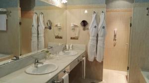a bathroom with two sinks and a mirror and towels at Hotel Duques de Medinaceli in El Puerto de Santa María