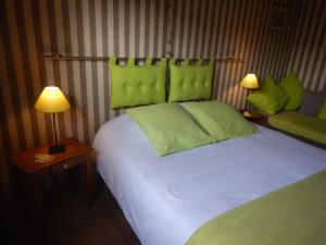 a bedroom with a bed with green headboard and two lamps at B&B La Chrysalide in Mons