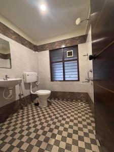a bathroom with a toilet and a sink and a window at Jaya Tourist Home in Varkala