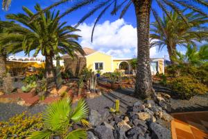 a house with palm trees in front of a yard at Villa MADORA - private pool, amazing garden, sea view, quiet location in Tías
