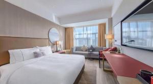 a hotel room with a large bed and a couch at Echeng Hotel Guiyang Exhibition Center Financial City in Guiyang