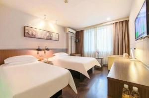 a hotel room with two beds and a flat screen tv at Jinjiang Inn Select Harbin Zhongyang Street Pedestrian Street Airport Bus Station in Harbin