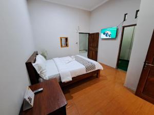 a bedroom with a bed and a table in a room at Romadhoni Homestay in Magelang