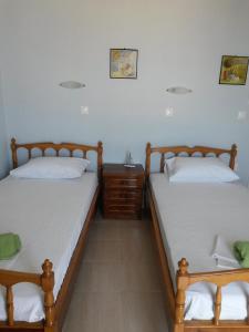 2 camas individuales en una habitación con mesita de noche en Drakopanagiotaki Rooms en Áyios Andréas Messinias